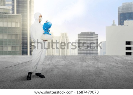 Man in a white protective suit spraying disinfectant at outdoor. Prevent the spread flu disease Coronavirus
