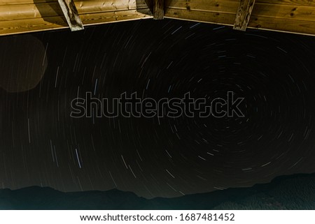 Long exposure of night sky under a roof