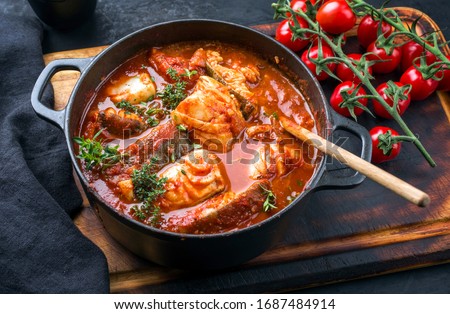 Traditional Brazilian fish stew moqueca baiana with fish filet in tomato sauce as top view in a modern design cast-iron roasting dish  Royalty-Free Stock Photo #1687484914