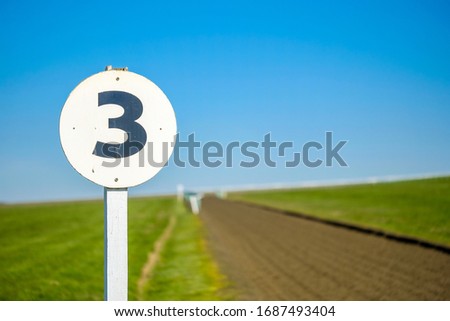 3 furlong distance marker seen on the edge of a professional flat-racing training track in the UK. The track extends to the distance before curving to the right up an incline.