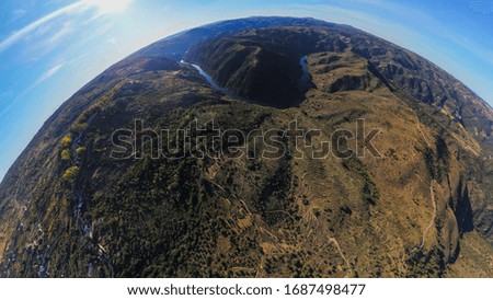 A 360 photography of a river in the middle of mountains under a blue sky