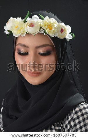 Portrait Beautiful Muslim Asian Girls with a checkered motif, a hijab with flower headbands, a photo in a studio on a black background