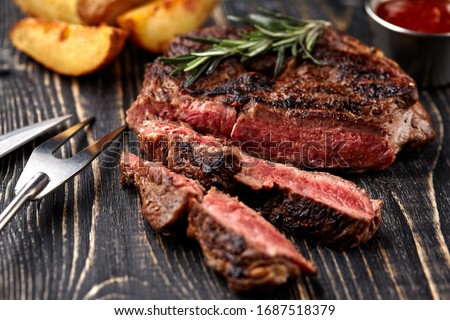 Juicy steak medium rare beef with spices on wooden board on table Royalty-Free Stock Photo #1687518379