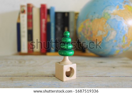 Christmas tree made of wood on a wooden floor Stacks of books and globes in the background