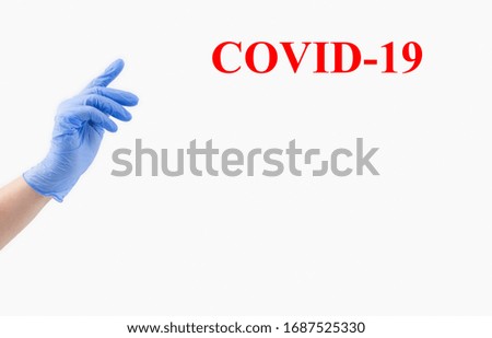 One hand of a woman doctor in a blue sterile medical glove on a white background, banner. With your index finger, reach for the top. copy space. Text Covid-19