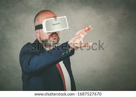 Portrait of businessman using VR glasses on gray background