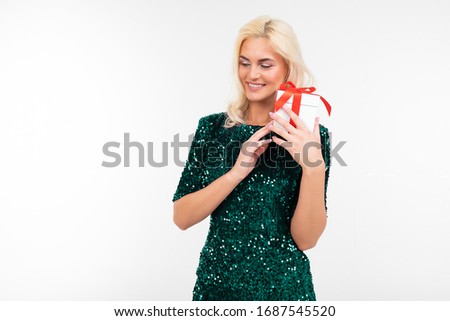 happy playing girl in a green shiny dress received a birthday present on a white background with copy space