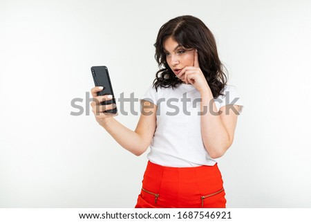 brunette girl is surfing the internet holding a phone in her hands on a white isolated background
