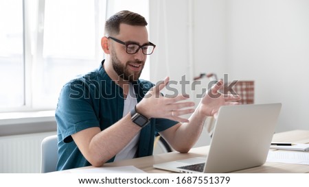 Millennial Caucasian male worker in glasses have video call on laptop in office, smiling young man employee talk speak engaged in online conference using computer gadget, communication concept Royalty-Free Stock Photo #1687551379