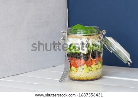Vegetables salad in a jar with fork tied with a rope on white wooden table. Inscription: stay home. Close up, copy space. Isolated. Healthy food, vegetarian dish, lunch or dinner. Homemade recipe. 