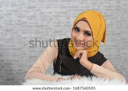 Portrait Beautiful Muslim Asian Girls wearing brown Muslim clothes and yellow hijab, a photo in a studio with a gray brick background