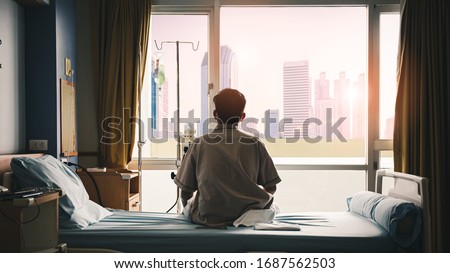 patient sat on the bed and looked out the window in the hospital alone and had stress, boredom, loneliness, anxiety. / Health care and medical Royalty-Free Stock Photo #1687562503