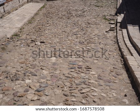old road paved with stone of various sizes lit by the sun