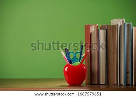 Composition with stationery and apple shaped pencil holder on table near chalkboard,copy space for text.