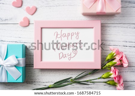 Design concept - top view of bunch of beautiful carnation with handwriting calligraphy and photo frame on white vintage wooden background for mother day mockup