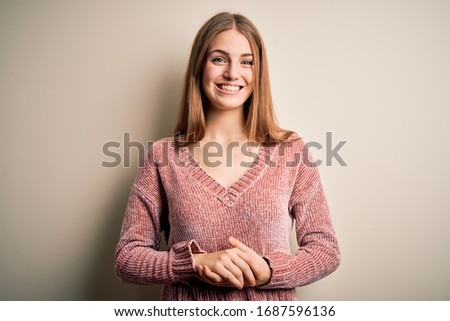 Young beautiful redhead woman wearing pink casual sweater over isolated white background with hands together and crossed fingers smiling relaxed and cheerful. Success and optimistic