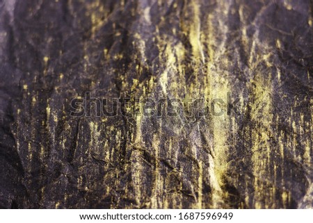 black crumpled surface with gold streaks for the background. black crumpled paper with yellow stripes top view