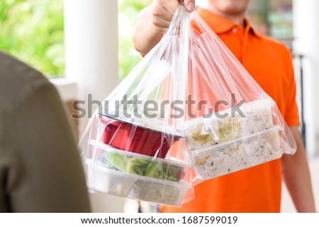 Delivery man giving lunch box meal in the bags to cutomer that ordered online at home Royalty-Free Stock Photo #1687599019