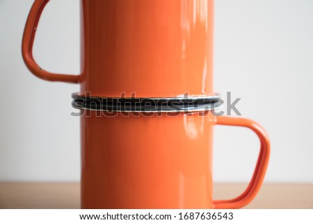 a pair of orange enamel camping cups 