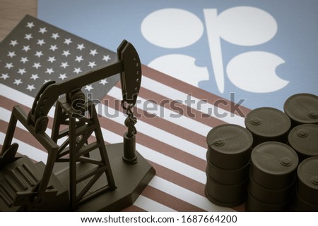 Spending or investment of a country's revenues from petroleum exports industry (Petrodollar). Oil pump jack on U.S. and OPEC flag background. Concept of crude oil price down plummet crisis, petroleum.