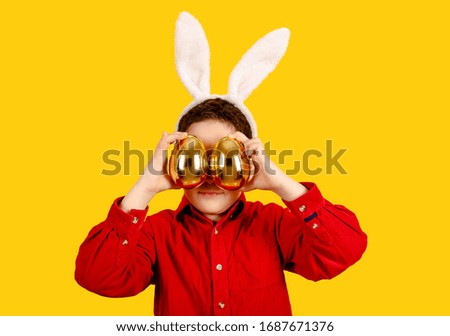 Beautiful child in bunny ears headband holding Golden Easter eggs