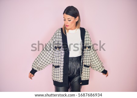 Young beautiful woman wearing fashionable clothes standing over isolated pink background