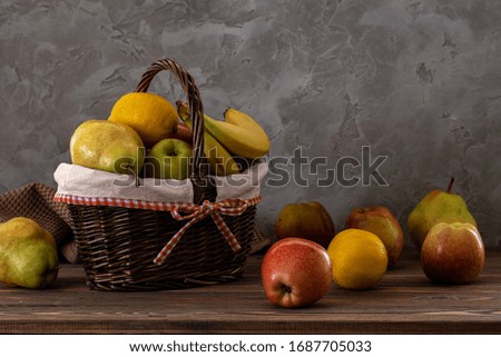 Still life fresh and juicy fruits in a basket on a wooden table against the background of an old wall