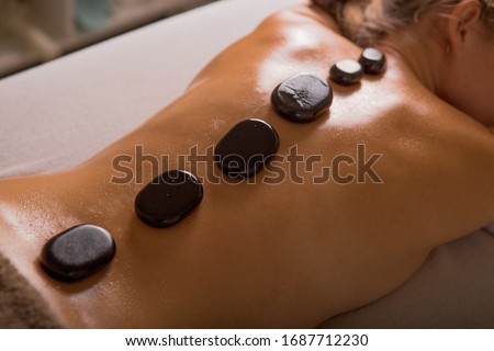 Top view of mature woman relaxing during hot stone massage Royalty-Free Stock Photo #1687712230