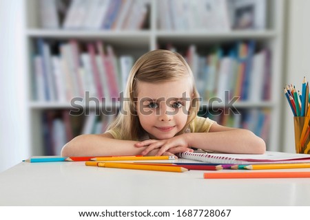 Cute child student with many books on the desk