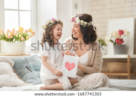 Happy mother's day! Child congratulating mom. Mum and daughter smiling and hugging. Family holiday and togetherness.                                                                                  
