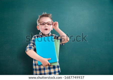 Funny happy child schoolboy on the school blackboard background