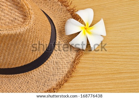 Frangipani tropical flower, plumeria and hat on wood background