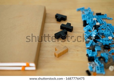 Plastic building blocks, brown notebook and wood blocks puzzle on wood table