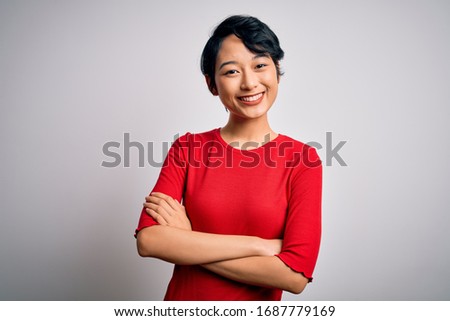 Young beautiful asian girl wearing casual red t-shirt standing over isolated white background happy face smiling with crossed arms looking at the camera. Positive person.