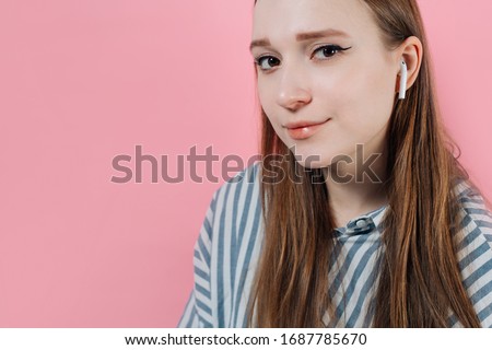 girl on a pink background with a white wireless headphone. Air Pods. with Wireless Charging Case. New Airpods 2019 on pink background. Airpods. female headphones. Copy Space