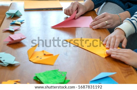 Close-up of a mother with her son while they are at home doing origami crafts