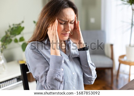 Young freelancer woman suffering with a headache at home office Royalty-Free Stock Photo #1687853092