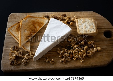 Cheese board with nuts, bread and tomatoes