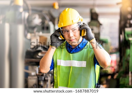 Professional technicians wear protective equipment and hard hats in large industrial plants. Protective and Safety Equipment eye wear, ear plug, vis clothes and protective helmet. Royalty-Free Stock Photo #1687887019