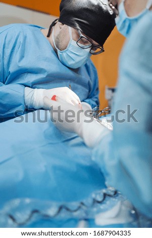 Doctor with surgical tools in hands making surgery in operation room. Health care and Hospital concept.