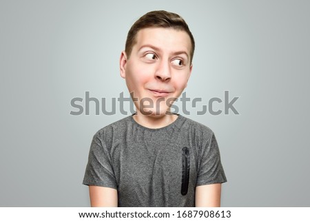 Funny cartoon portrait big head of a young guy in a gray T-shirt with vivid emotion of surprise and joy. Surprised man with big head