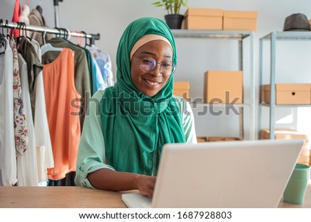 Muslim woman small business in her own home. Is the design and tailoring of clothes. Happy beautiful muslim business woman working about financial with business report and calculator in home office