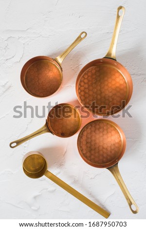 Copper utensils on the white background. Vintage copper cookware - cocottes, creamer and accessories for coffee.  Royalty-Free Stock Photo #1687950703