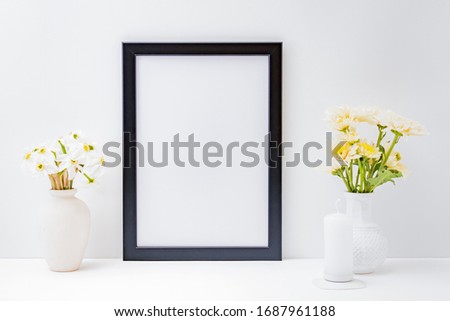 Home interior with decor elements. Mockup with a black frame and flowers in a vase on a light background