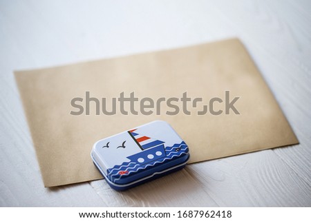 craft envelope for letters and a metal gift box with a boat on a white wooden background