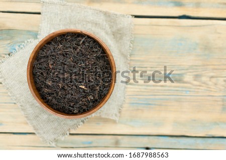Lot of pieces of dry black tea with wooden bowl and wooden scoop