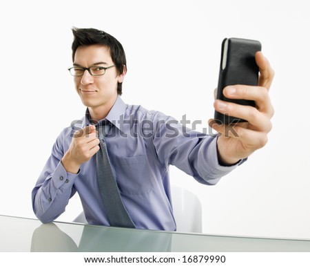 Businessman taking photograph of himself using pda or smart phone device.