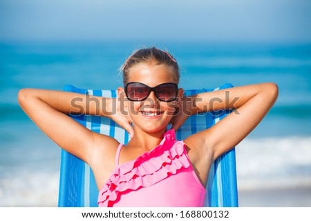 Portrait of young beautiful girl relaxing on deck chair on the beach.