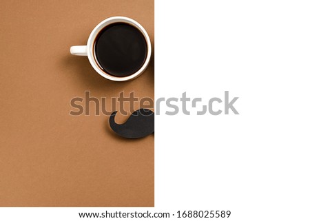 Close up of hot cup coffee, stylish black paper photo booth props moustaches on brown and white background. Copy space for inscriptions. Creative idea, minimal composition