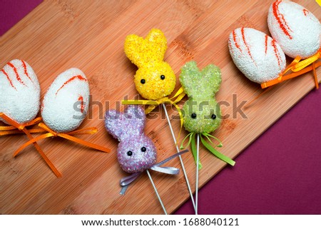 Easter composition with eggs and multi-colored rabbits on a wooden background. Holiday picture